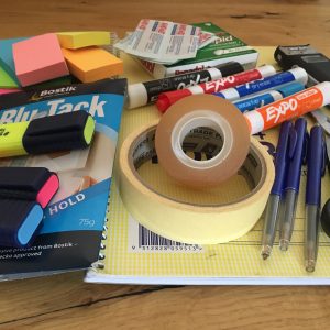 stationery spread out, including pens, highlighters, tape, paper and sticky notes