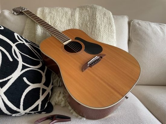 classic guitar on white couch with cushions